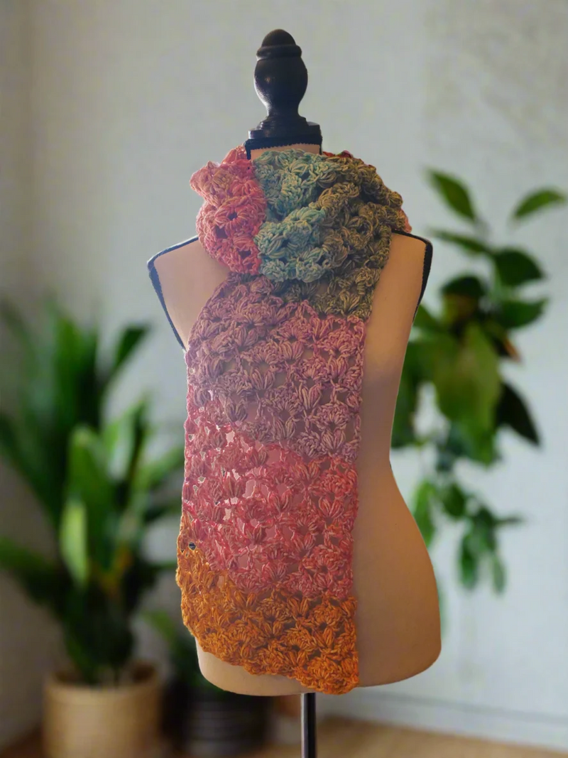 Colorful crochet Sweetheart scarf draped around a dress form, with textured lace stitches in soft pink, coral, yellow, teal, and green.