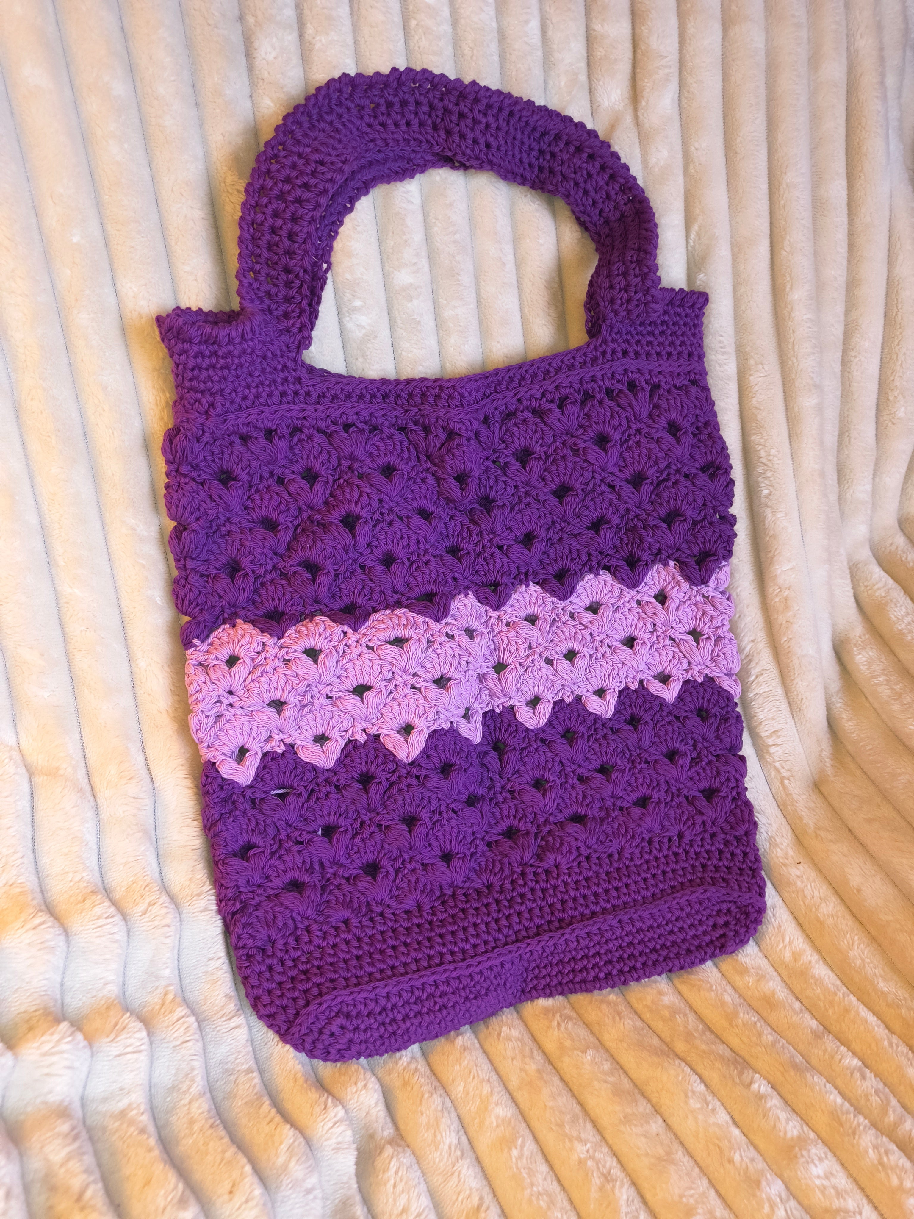 Purple and pink textured bag on beige blanket