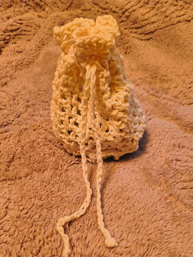 Handmade crochet drawstring bag with three reusable cotton scrubbies for makeup or jewelry storage