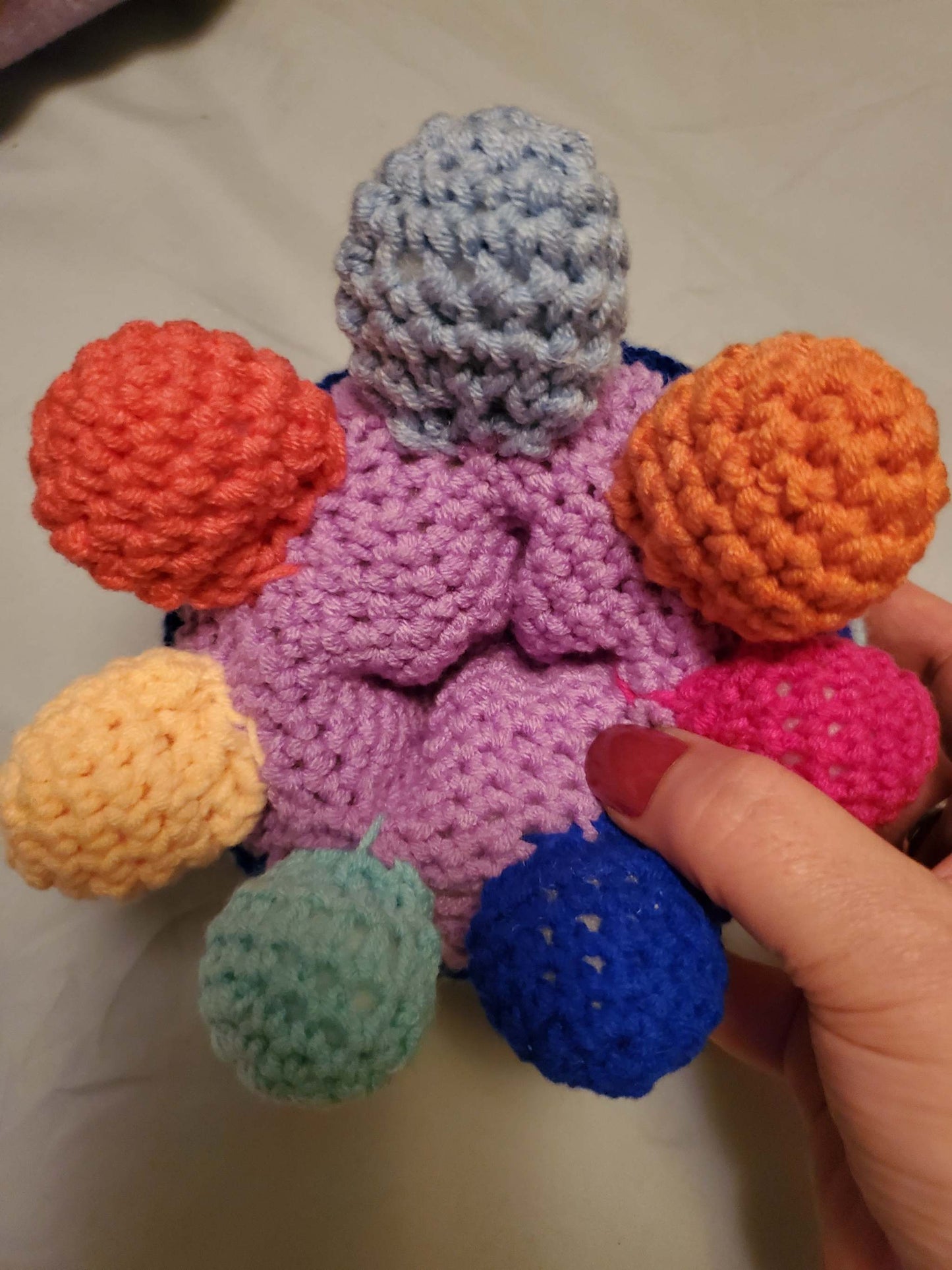 Handmade crocheted rainbow octopus toy with colorful tentacles and hidden compartment.