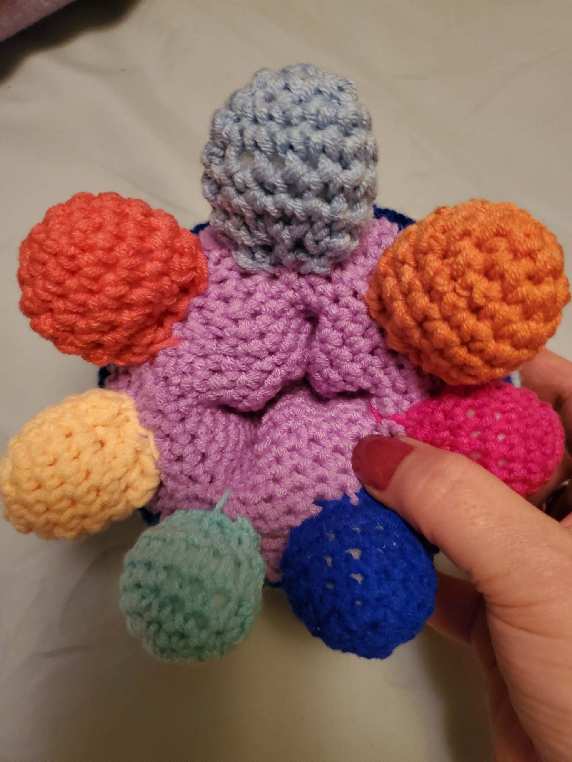 Handmade crocheted rainbow octopus toy with colorful tentacles and hidden compartment.