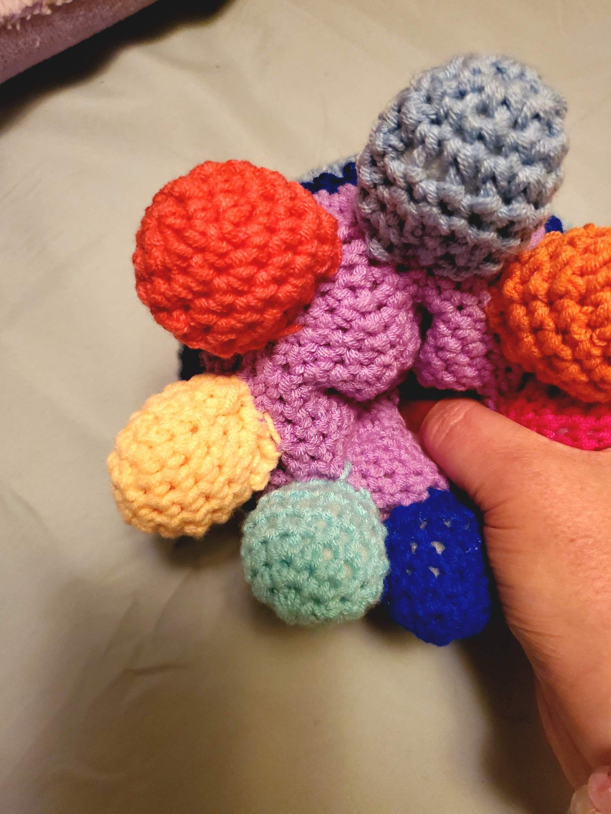 Handmade crocheted rainbow octopus toy with colorful tentacles and hidden stash compartment.