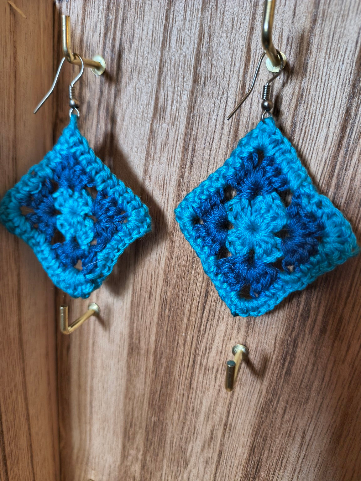 Handmade blue and teal crochet granny square dangle earrings with diamond-shaped motifs and silver-tone hooks