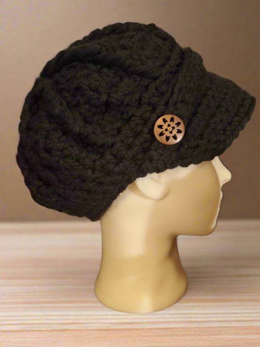 black crochet newsboy hat with chunky texture and wooden button on mannequin head