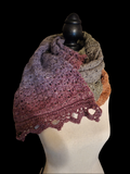 Handmade oversized crochet shawl wrap featuring puff stitches, lace detailing, and multiple textured stitch patterns in olive green, mauve, plum, cream, and copper tones draped on a dress form.