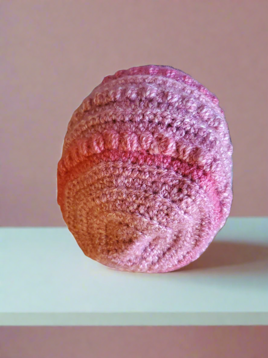 Beautifully crocheted soft pink hat on shelf, holiday accessory for women and teens.