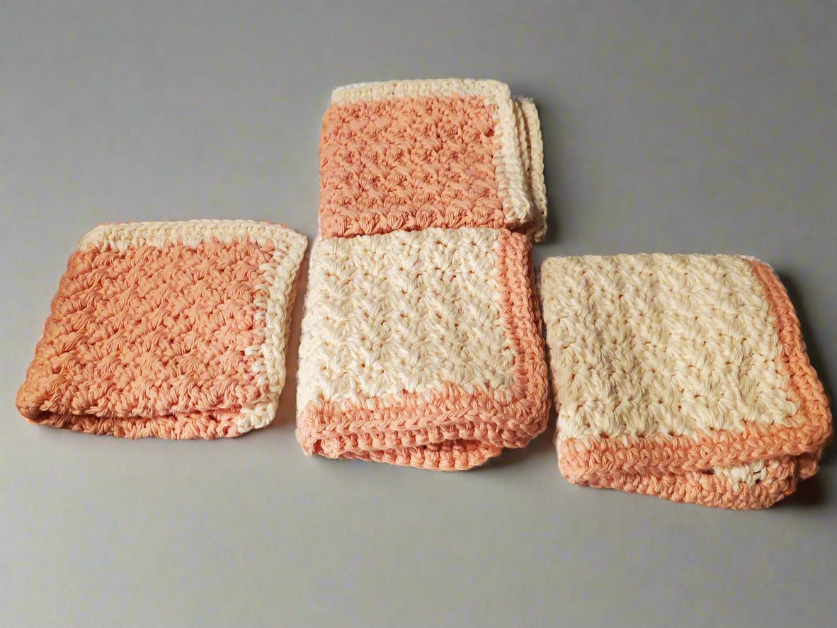 Set of four crocheted cream and tangerine dishcloths.