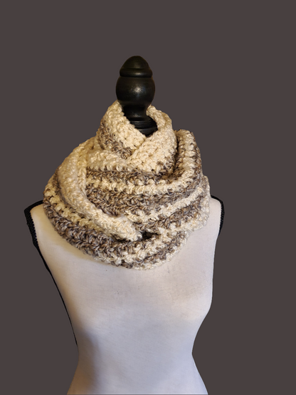 Handmade crochet chunky infinity scarf in cream and taupe tones with a thick textured stitch, oversized and extra warm, wrapped around a dress form.