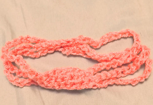 Soft pink crochet baby headband with simple textured center and stretchy band, handmade newborn headband laid flat on a neutral background