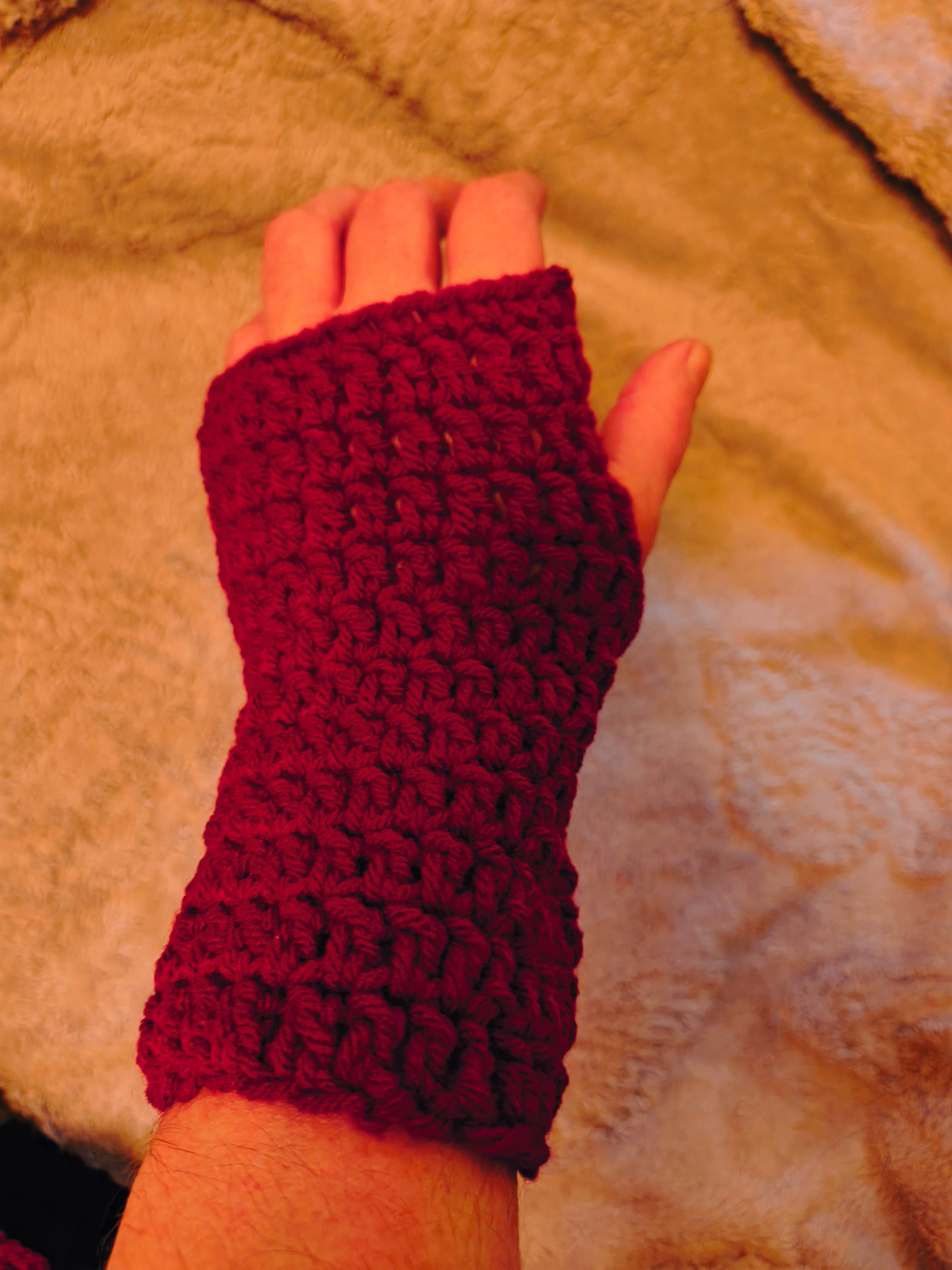 Red crochet fingerless gloves worn on hands, featuring a simple textured pattern and lightweight soft yarn for everyday use.