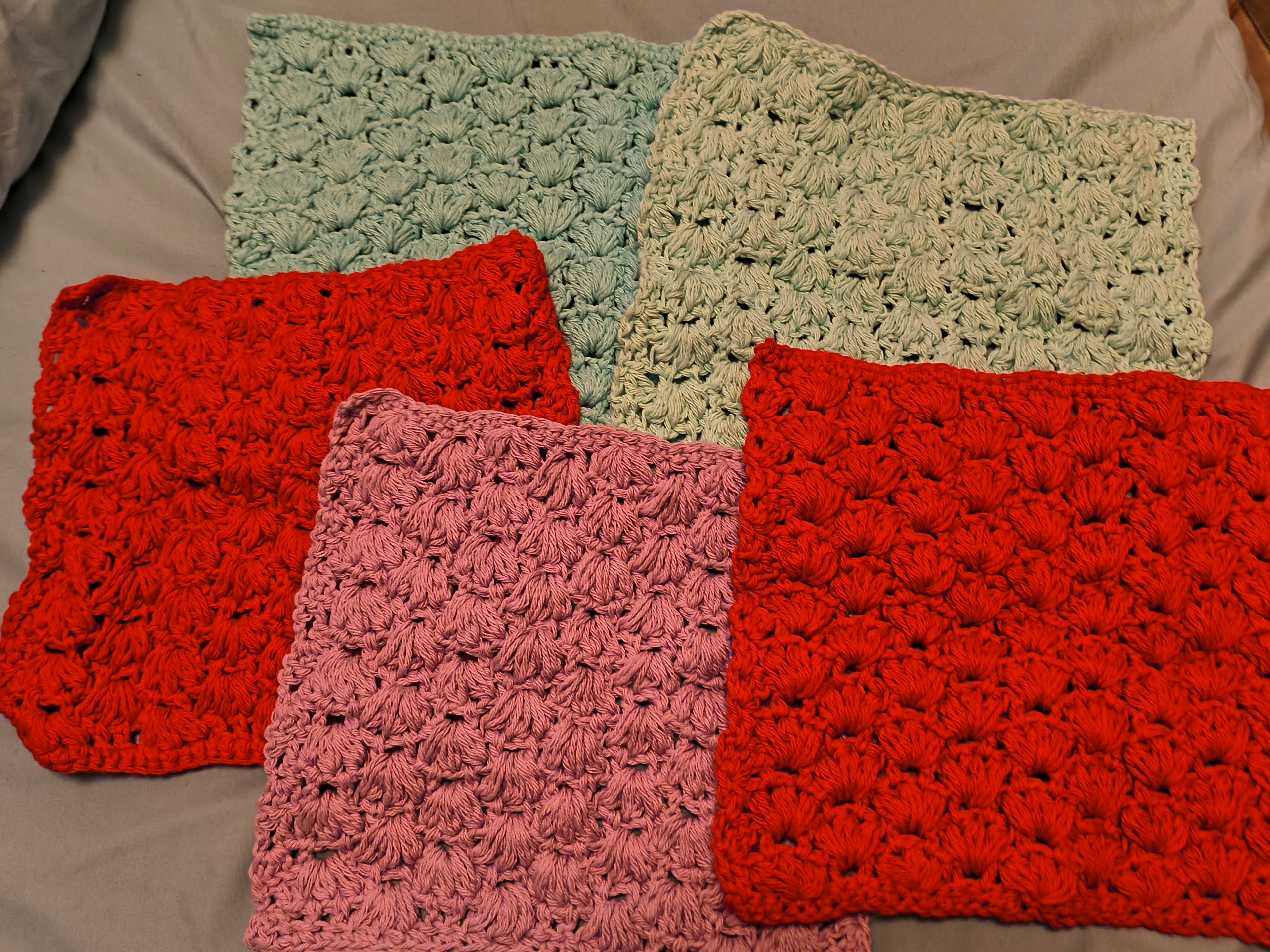 Handmade set of five cotton puff stitch washcloths in red, aqua, light aqua, and pink, arranged together showing thick textured design, approximately 10x10 inches each