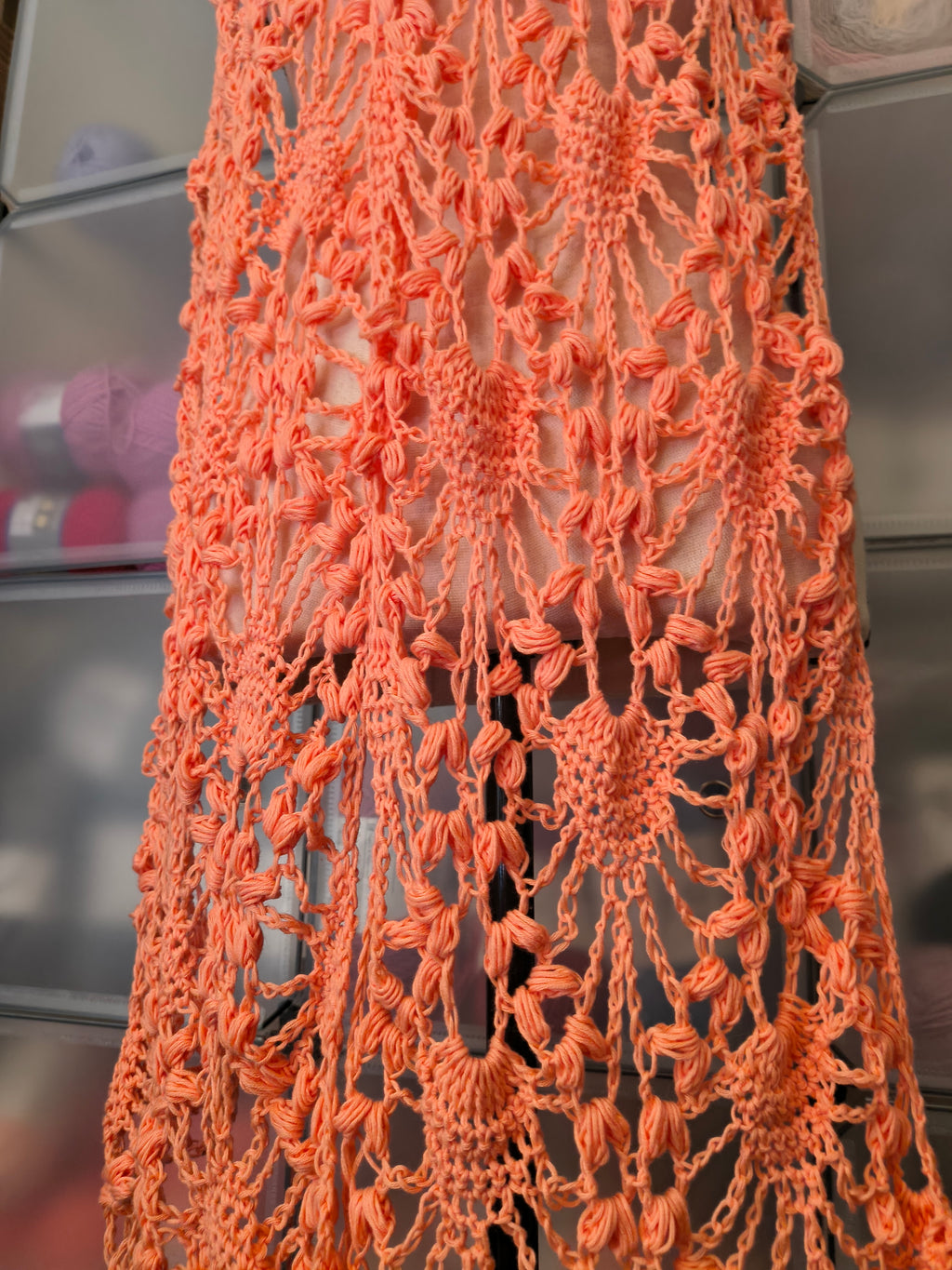 Close-up of coral crochet lace showing intricate puff stitch texture and openwork details.