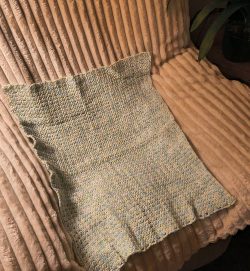 Handmade crochet baby blanket in soft blue, green, and white tones, lightweight stroller size with textured stitch detail, measuring approximately 29 by 22 inches