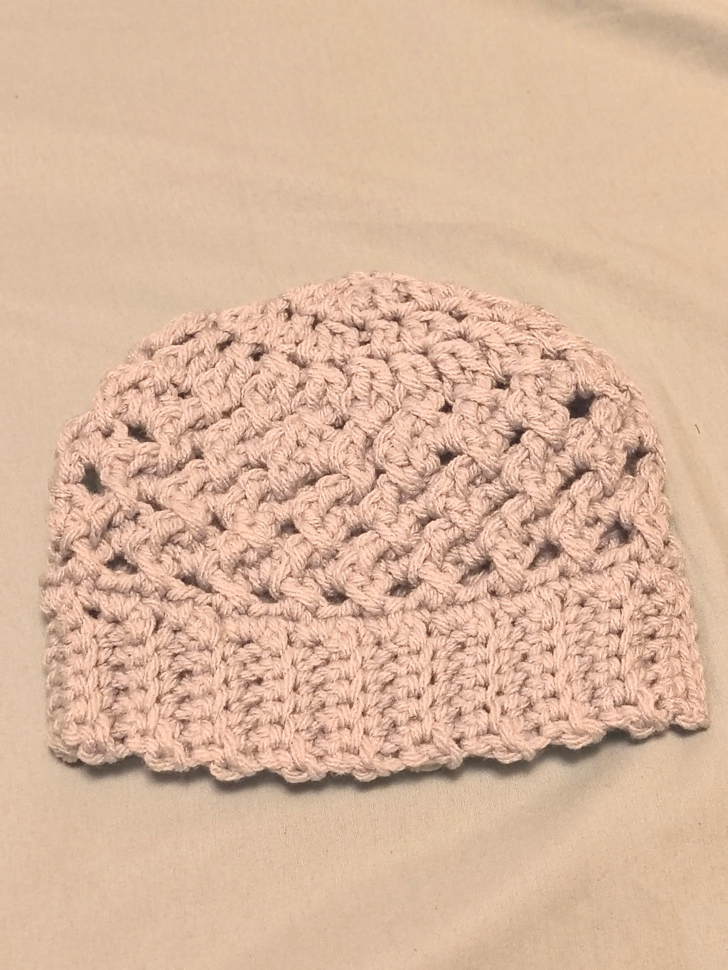 Silver gray crochet baby hat with textured stitch pattern and ribbed brim, handmade newborn beanie laid flat on a neutral background