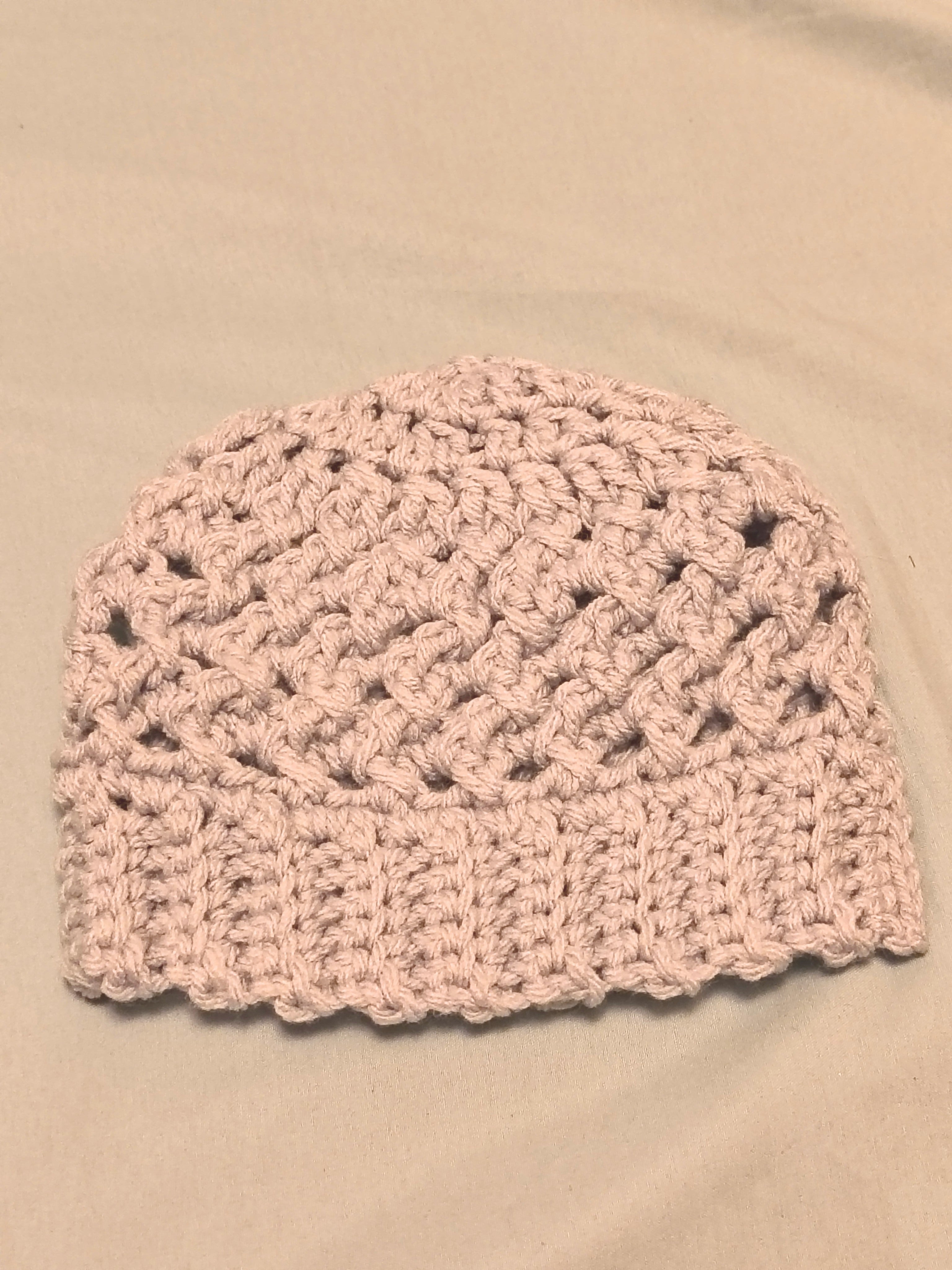 Silver gray crochet baby hat with textured stitch pattern and ribbed brim, handmade newborn beanie laid flat on a neutral background