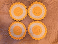Four yellow and white cotton coasters set, sunflower, flower design laid out on soft lavender blanket