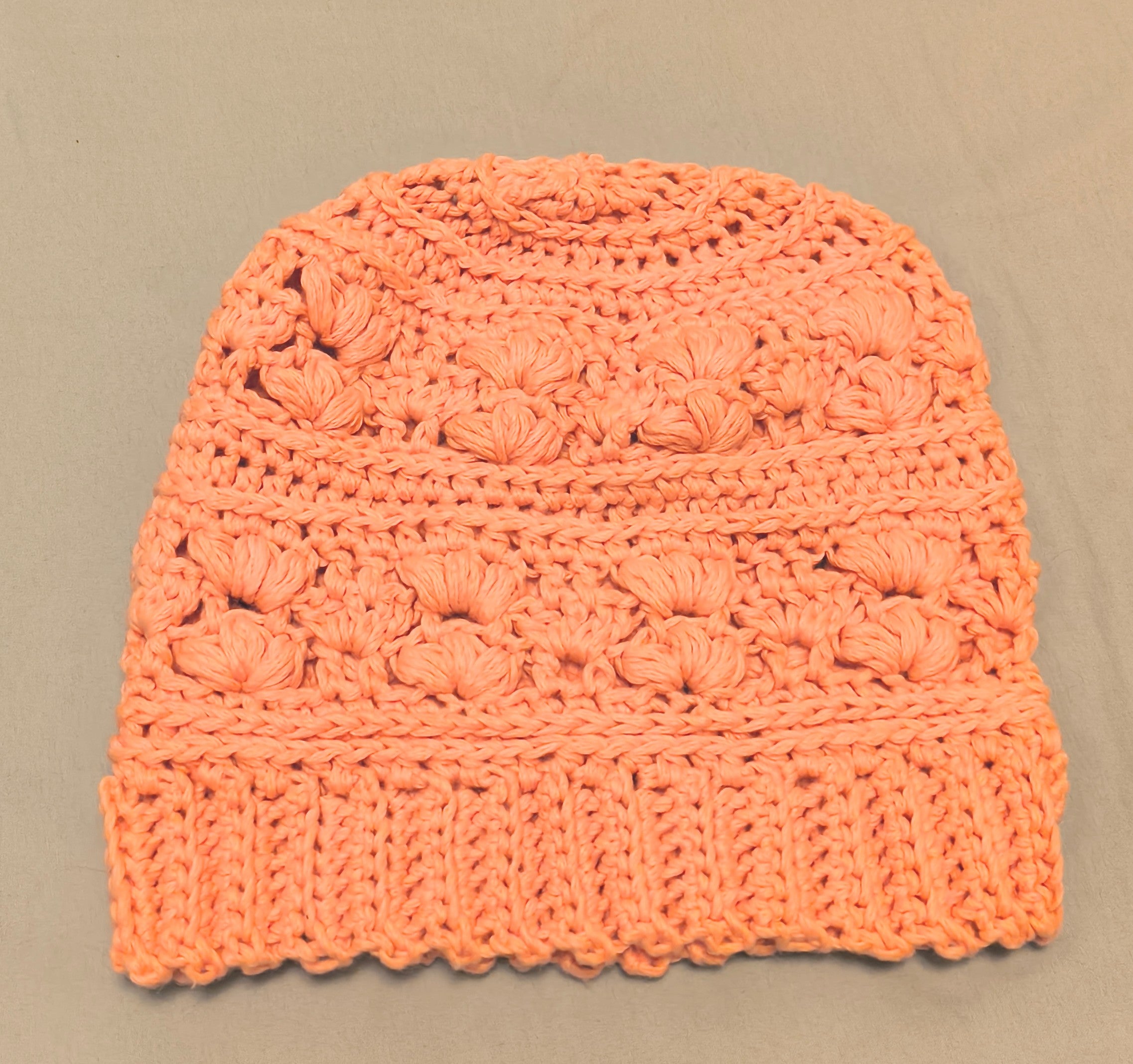 Peach crochet beanie made with cotton blend yarn, lightweight textured handmade hat laid flat on a neutral background