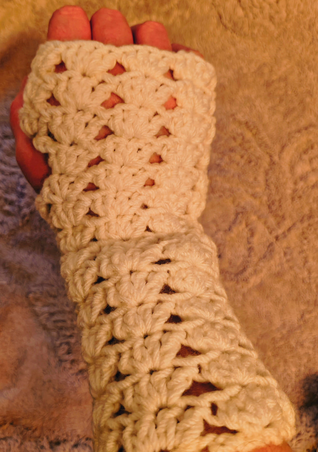 White crochet fingerless gloves worn on hands, featuring a delicate lace pattern and lightweight soft yarn, shown in natural lighting.