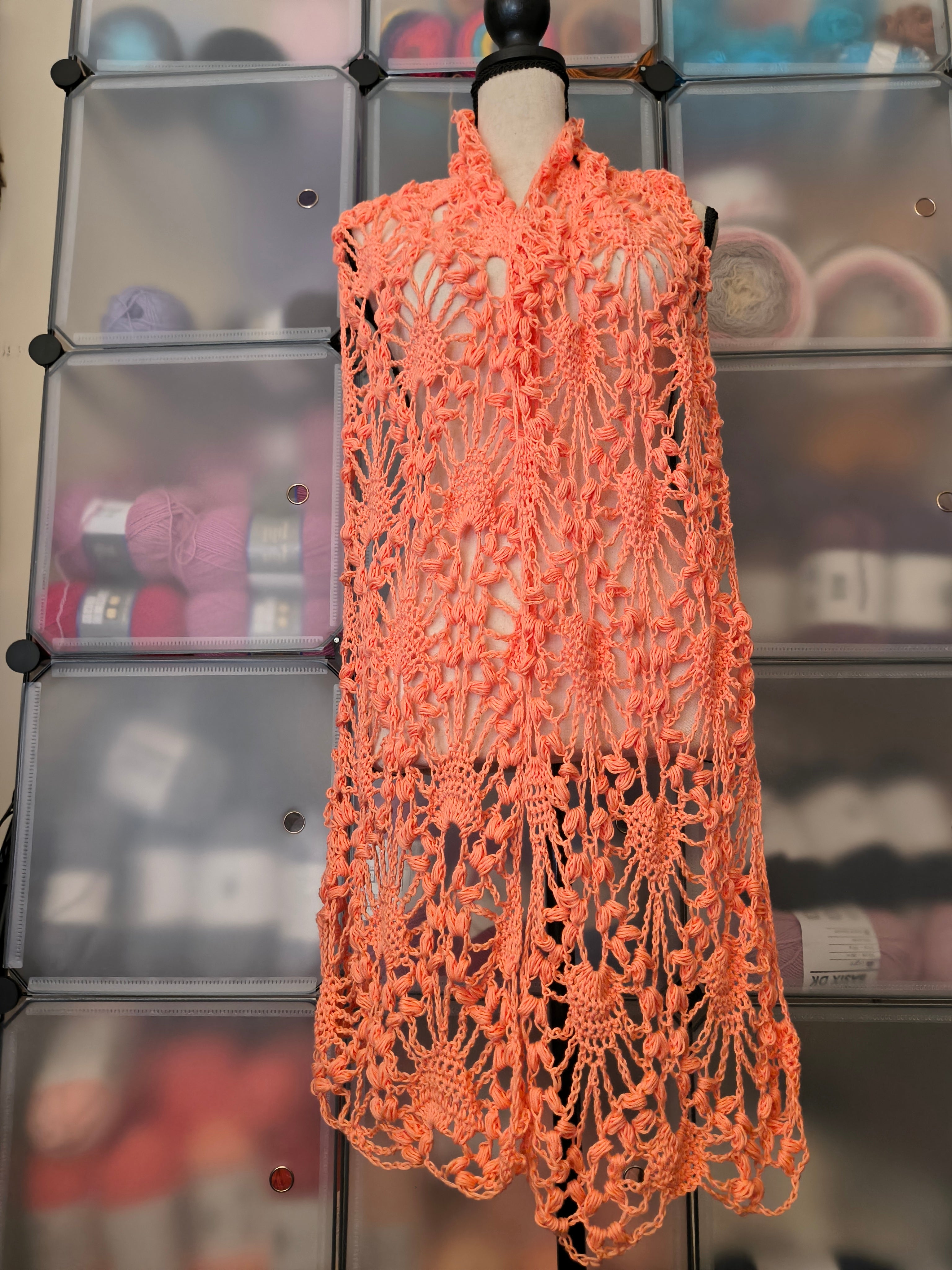 Oversized coral cotton crochet scarf draped over a mannequin to show its generous width and wrap styling.